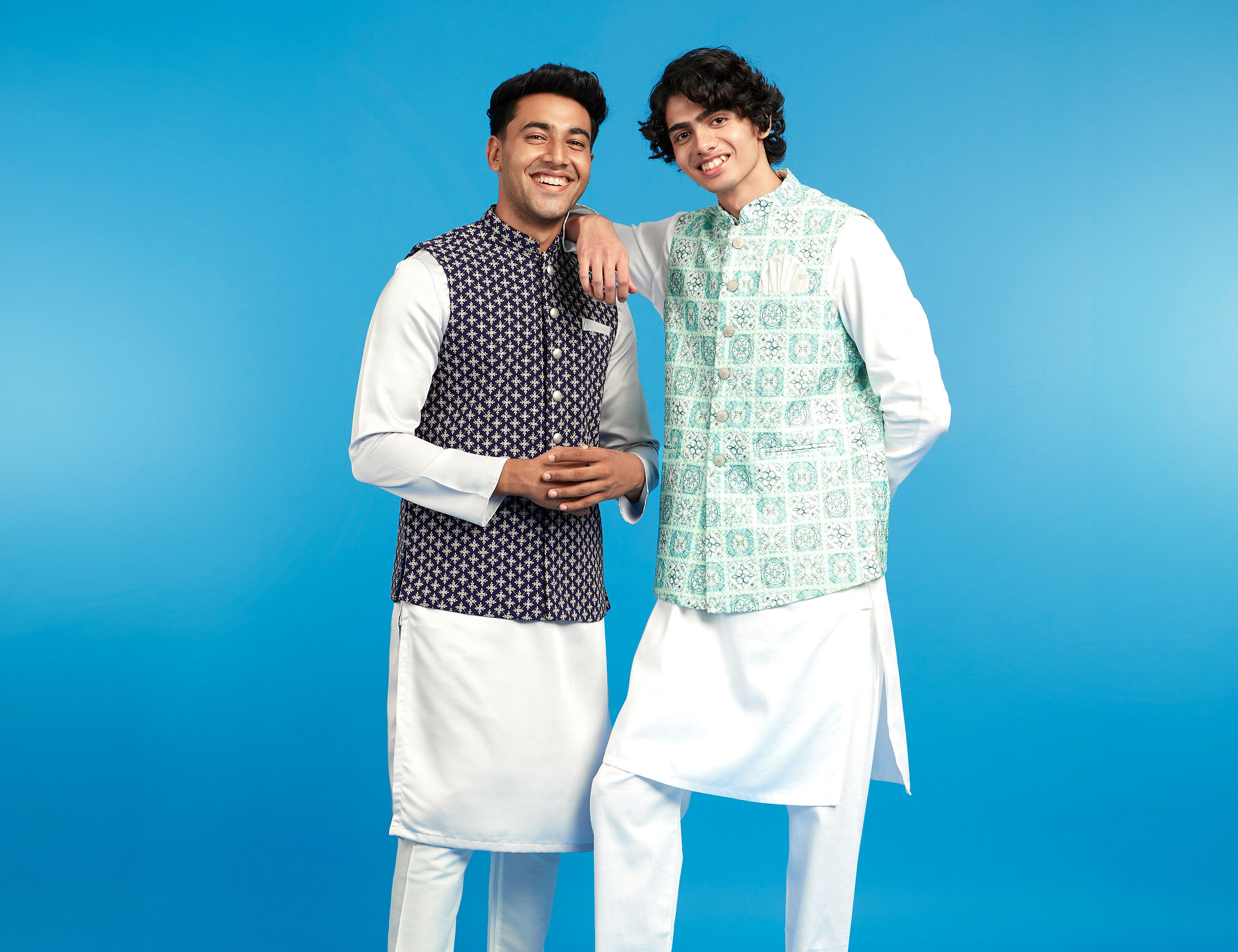 Two men in layered kurta ensembles featuring Nehru jackets showcase how structured layering, vertical lines, and streamlined fits help create balanced proportions for shorter men.